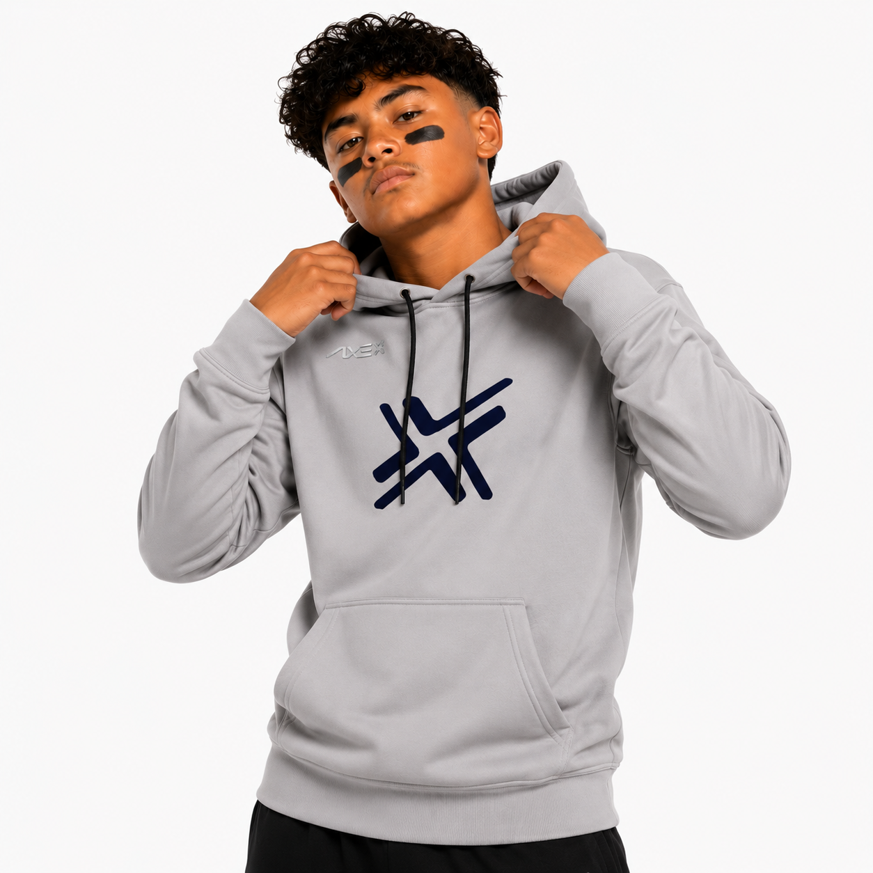 A young man wearing a light gray pullover hoodie with a dark navy graphic logo on the chest, posing against a solid white studio background.