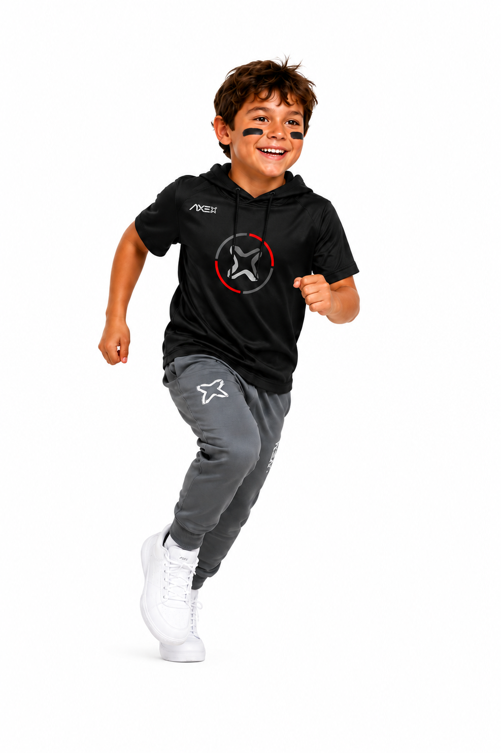 A young boy smiling and running in a black short-sleeve hoodie with a white and red star logo, paired with gray jogger pants and white sneakers, on a solid white background.