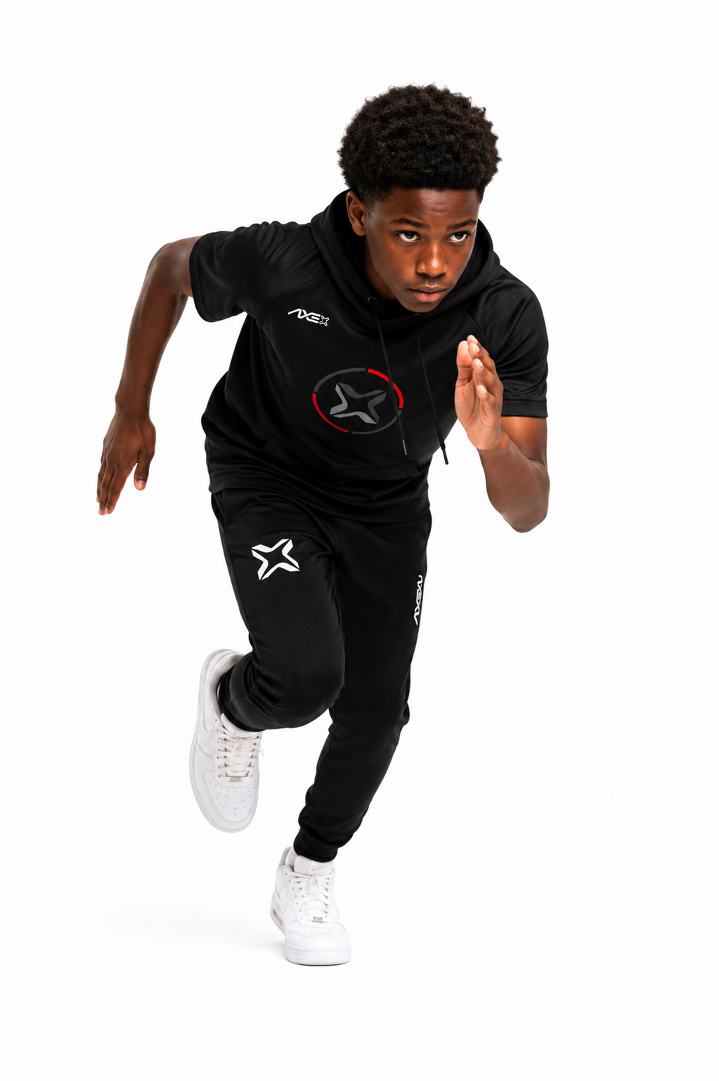 A young boy running forward in a black athletic tracksuit with white sneakers, featuring a black hoodie and matching joggers with white and red star graphics, on a solid white background.