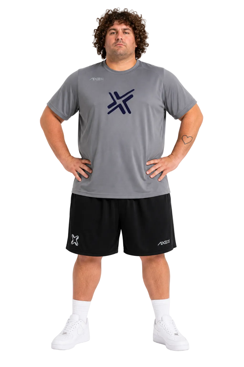 A man modeling a gray athletic t-shirt and black athletic shorts set with white socks and sneakers, featuring a dark navy blue logo on the chest.
