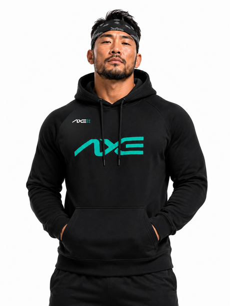 A man wearing a black pullover hoodie with a large teal and white AXE logo on the chest, paired with black pants and a black headband, against a plain white background.