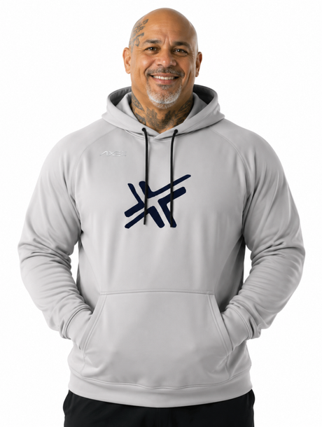 A smiling man wearing a light gray pullover hoodie with a dark navy stylized logo on the chest, photographed against a plain white background.