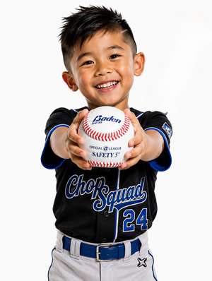 A young boy smiling and holding a white baseball with red stitching toward the camera. He is wearing a black and blue Chorusquad baseball jersey with the number 24 and gray pants against a plain white background.