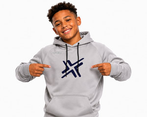 A smiling young man wearing a light gray hoodie with a dark blue stylized logo on the chest, pointing at the logo with both hands against a plain white background.