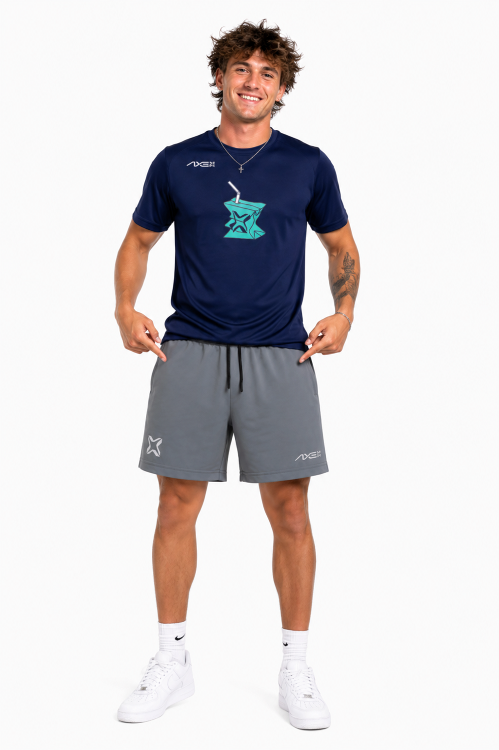A man modeling a navy blue athletic t-shirt with a teal graphic and gray athletic shorts, standing against a plain white background.