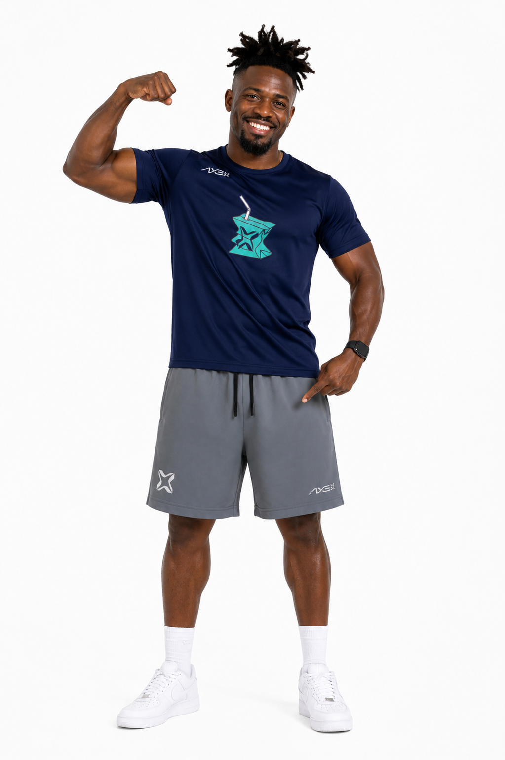 A man modeling a navy blue athletic t-shirt with a teal star logo and gray athletic shorts, posing with one arm flexed against a plain white background.