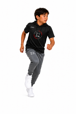A child running in a black short-sleeve hoodie with a red and white star logo and gray jogger pants with a white star logo, paired with white sneakers, on a solid white background.