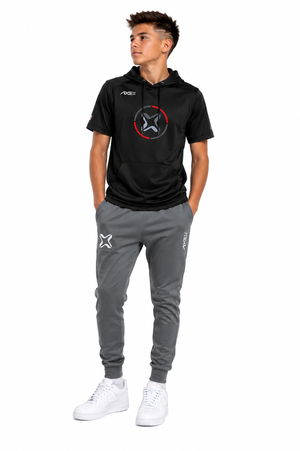A young man modeling a black short-sleeve hoodie with a red and white circular logo on the chest, paired with gray jogger pants and white sneakers, against a plain white background.