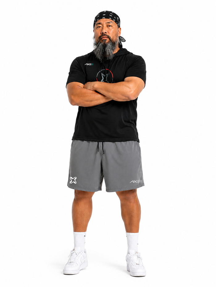 Man wearing gray Axe Training Shorts with the white Axe X mark at the left hem, paired with a black Axe performance tee.